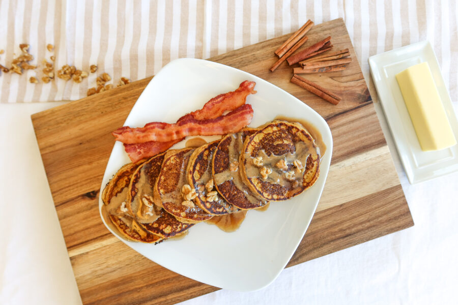 Pumpkin spice pancakes and bacon on a large, white plate.