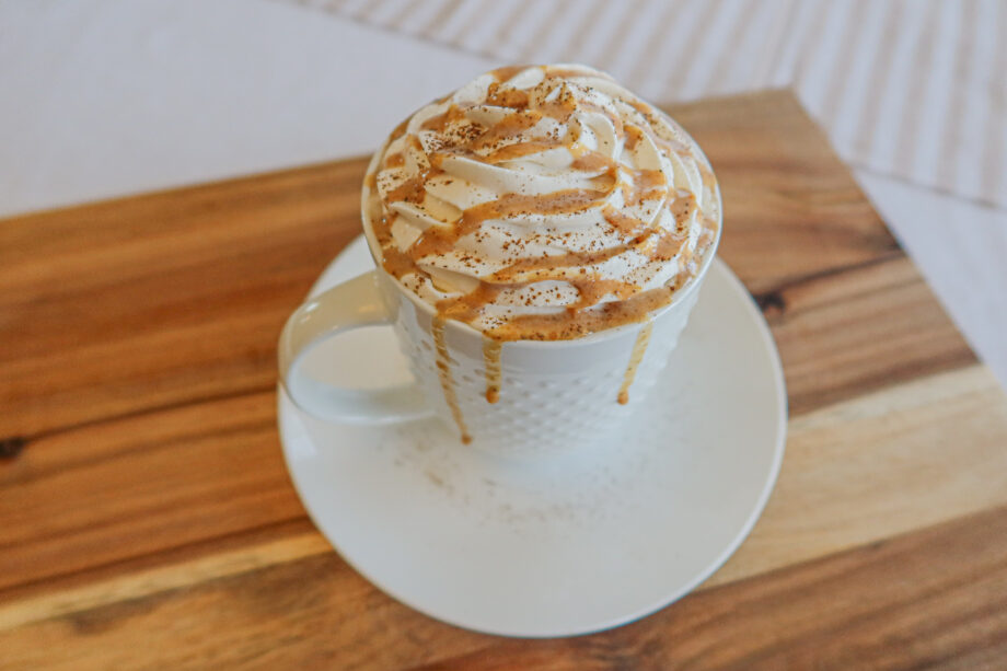 A cup of coffee with whip cream drizzled in pumpkin spice sauce.