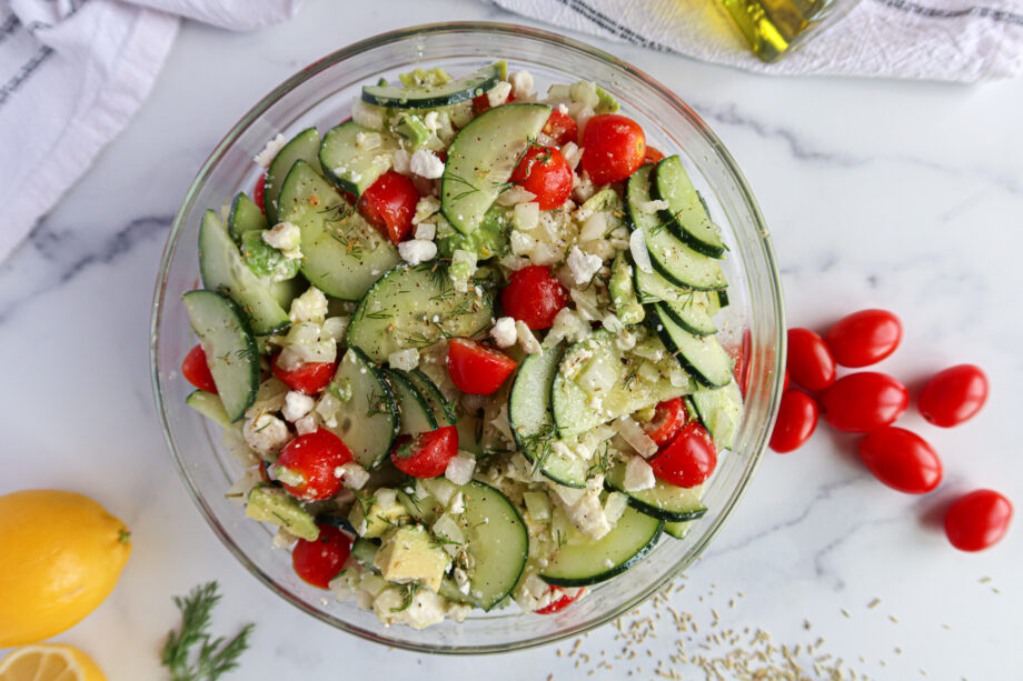 Cucumber And Onion Salad all mixed up with dressing in a glass bowl.