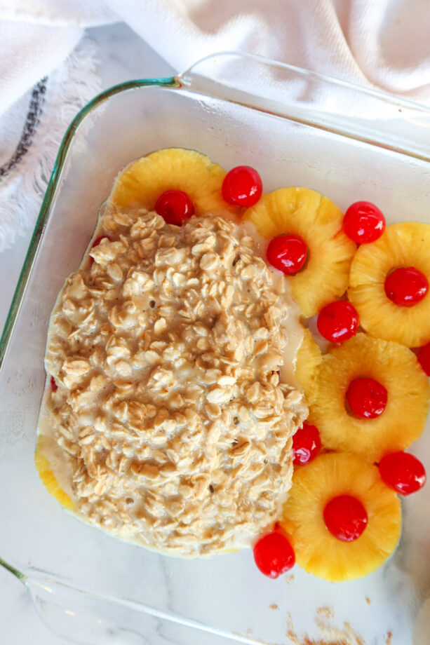 Pouring oatmeal batter over pineapples and maraschino cherries. 