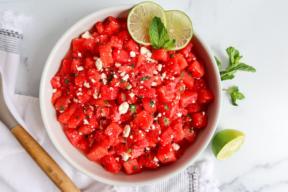 Watermelon mint feta salad in a white serving bowl with a wooden spoon to the side.