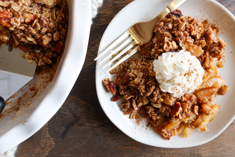 Easy, gluten free apple crisp on a small white plate with a gold fork. The rest of the crisp sits to the side in a pie dish.