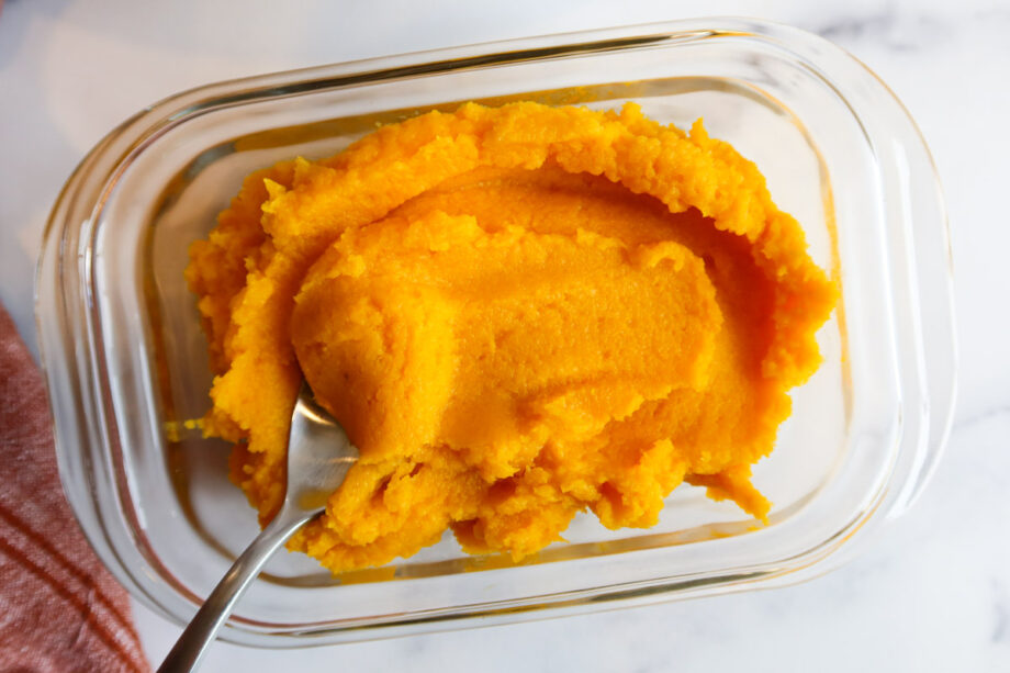 Homemade pumpkin puree in a glass storage container. 