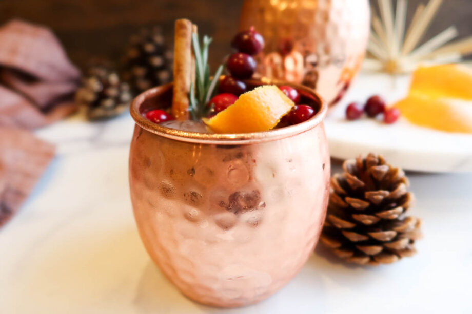 Close of a cranberry orange Moscow mule with garnish in a hammered copper mug.