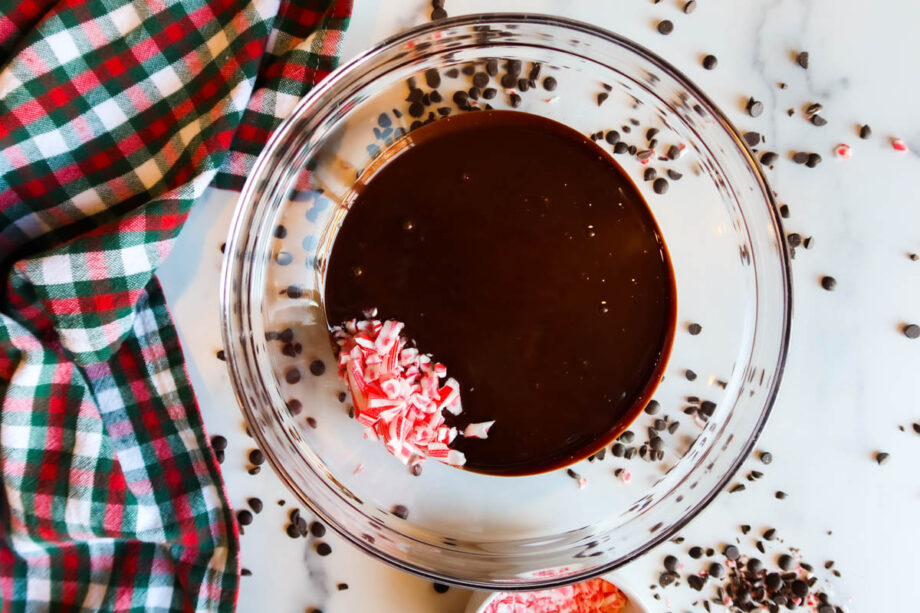 Melted chocolate and crushed candy cane pieces in a glass bowl.