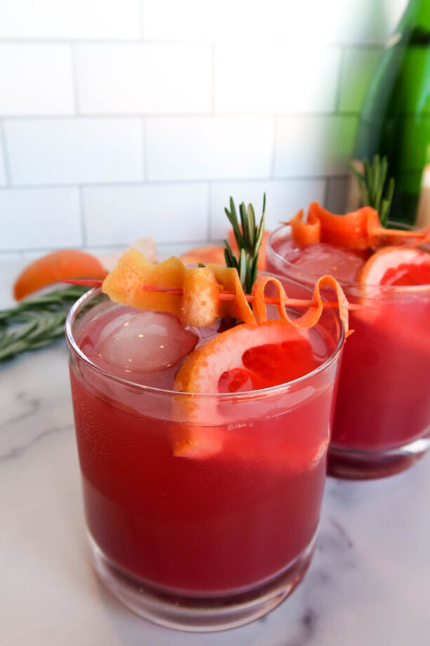 Pink, sparking paloma cocktails on a white countertop.