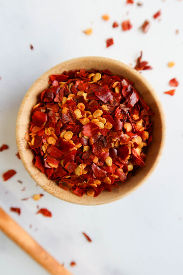 Dried and crushed red pepper flakes in a small, bamboo bowl. 