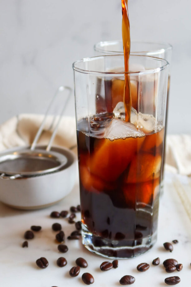 Pouring black cold brew over ice.