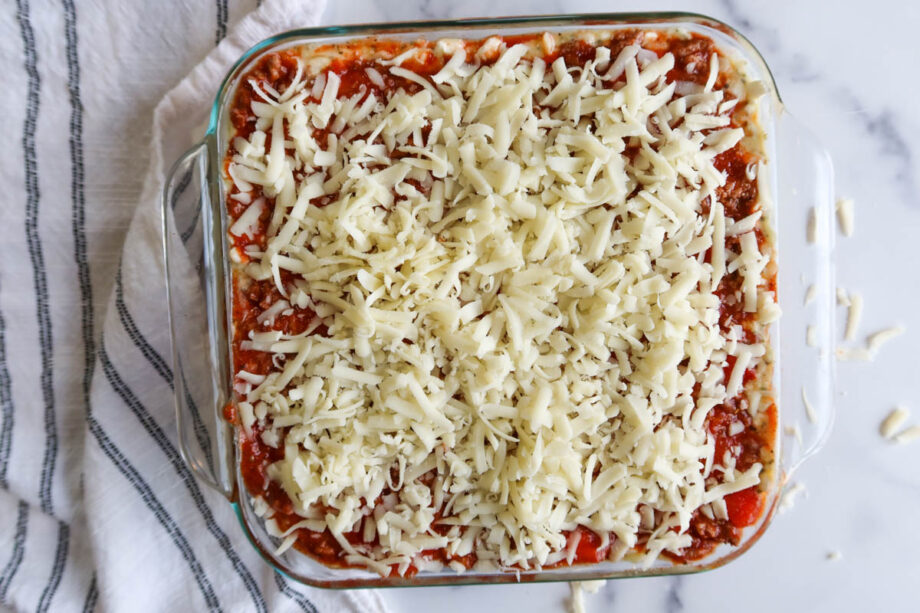 Assembled spaghetti squash lasagna covered in shredded mozzarella cheese.