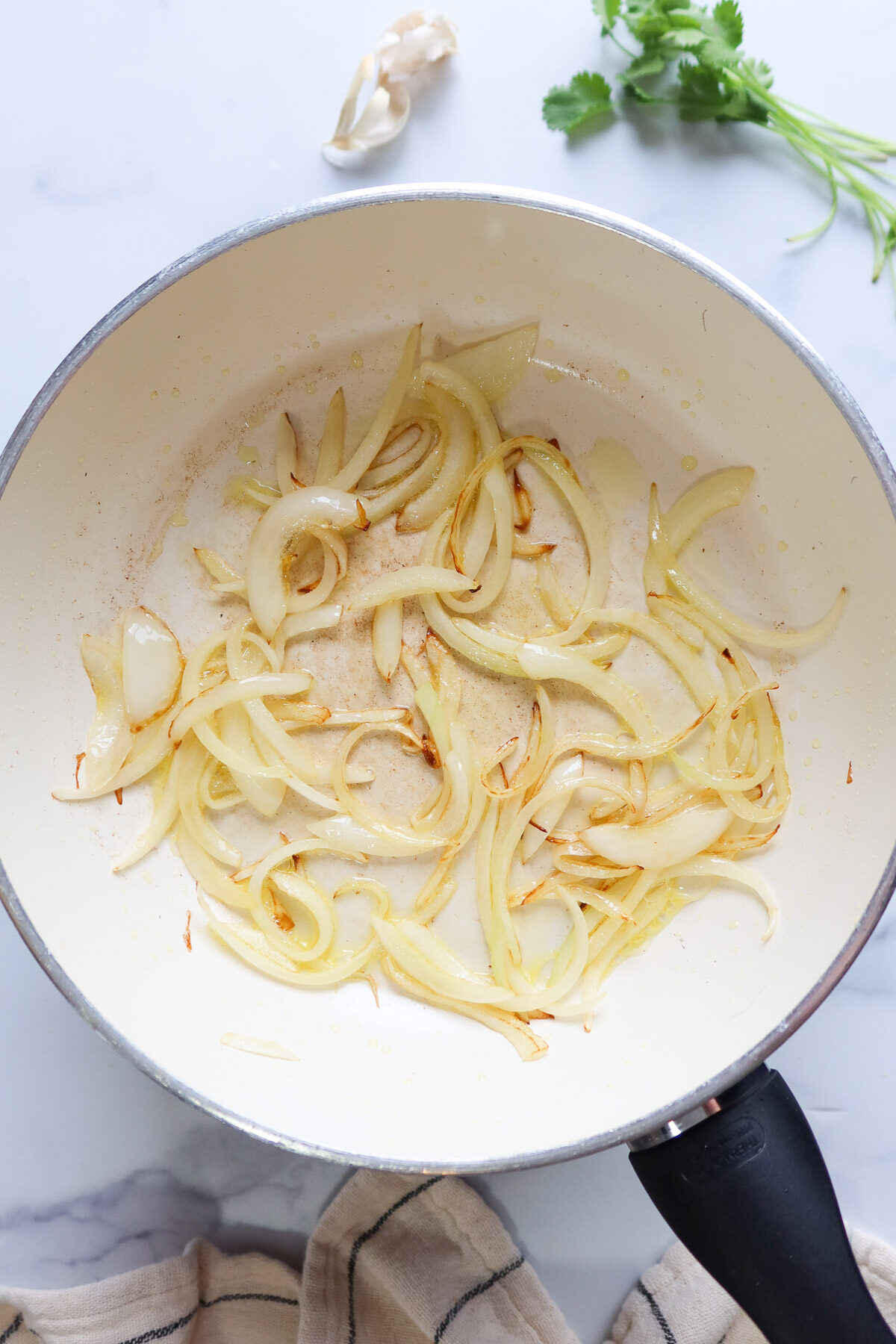 Sautéing onions in a white frying pan.