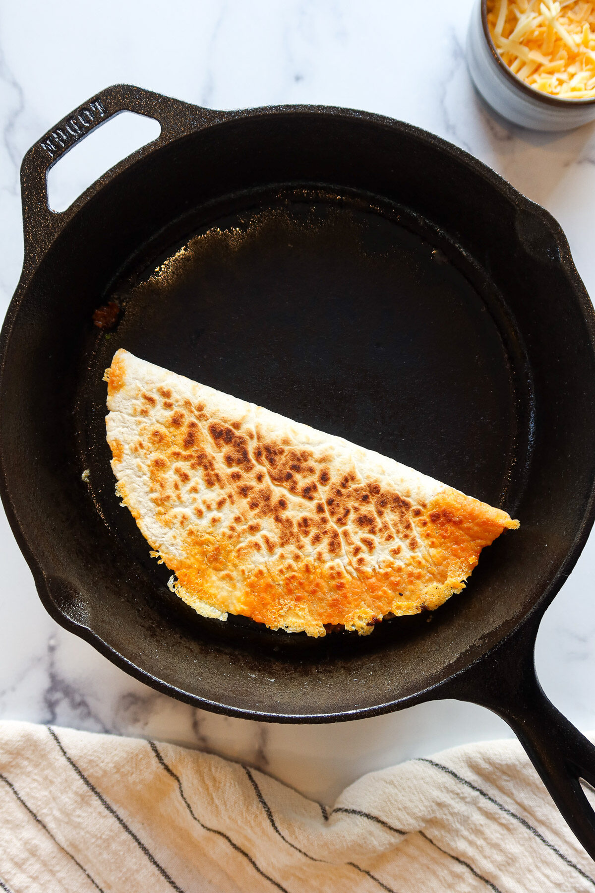 Cooking a quesadilla in a black cast iron pan.