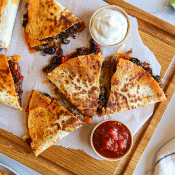 Chorizo quesadillas cut into pieces and arranged on a cutting board.
