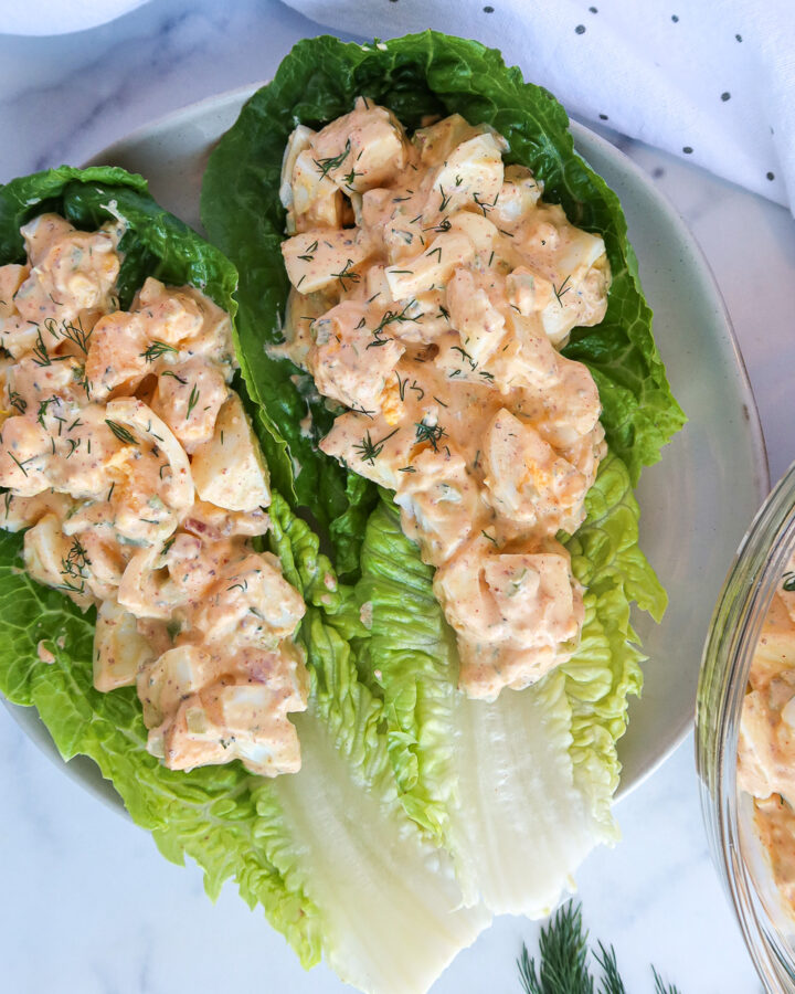 Greek yogurt egg salad on large, romaine lettuce leaves.