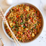 Ham fried rice in a white serving dish with chopsticks.