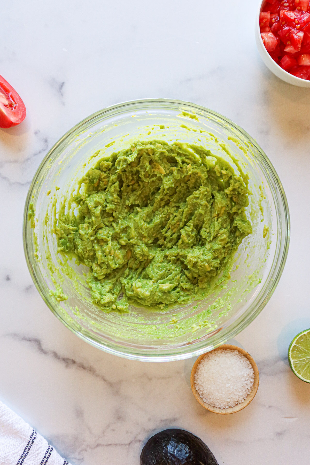 Mashed avocados in a glass mixing bowl.