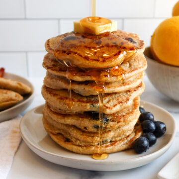 Syrup dripping down a stack of blueberry oatmeal pancakes.