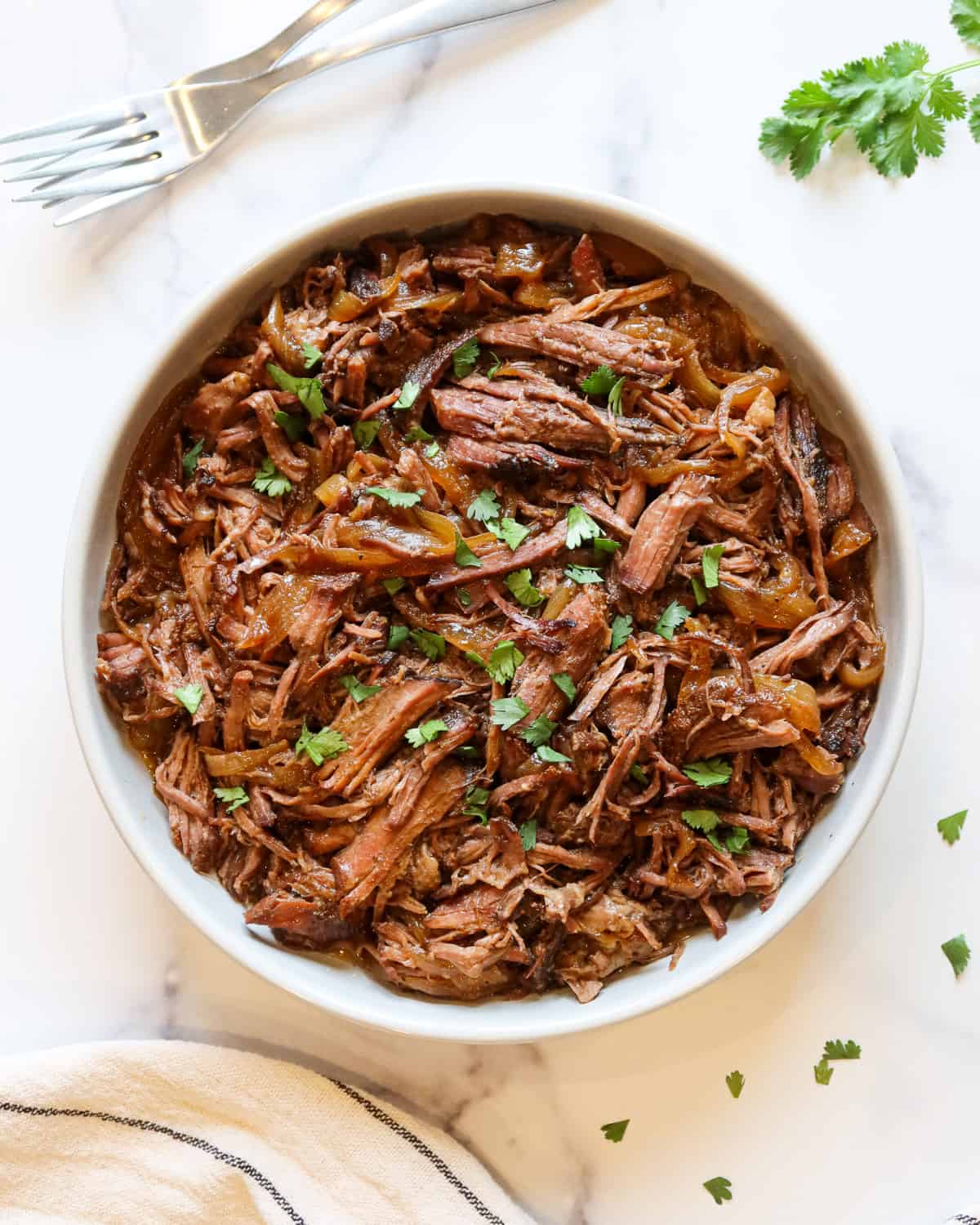 Slow cooker Mexican shredded beef in a white serving bowl.