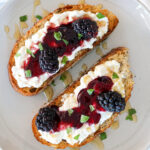 Blackberry burrata cheese toast with honey and fresh basil leaves.