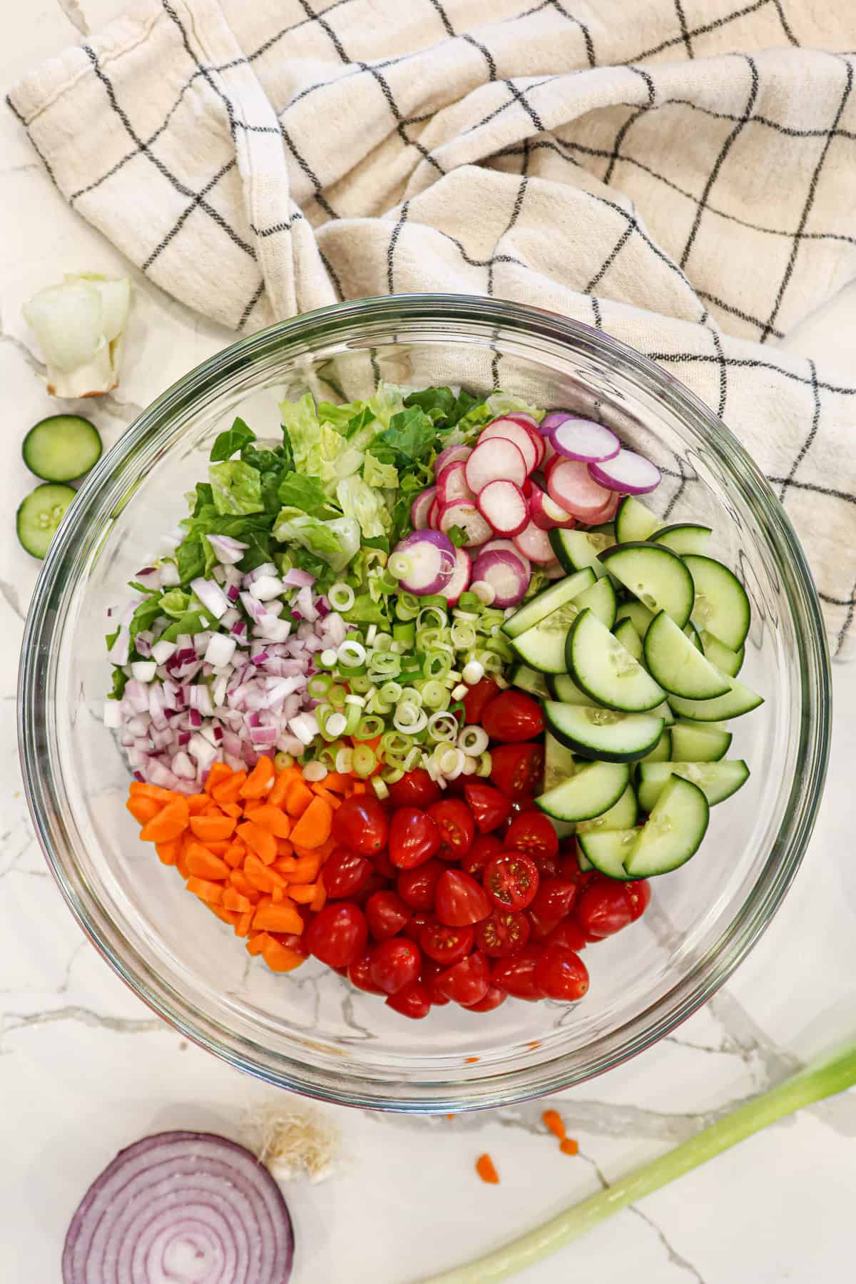 Garden salad ingredients measured into a glass mixing bowl.