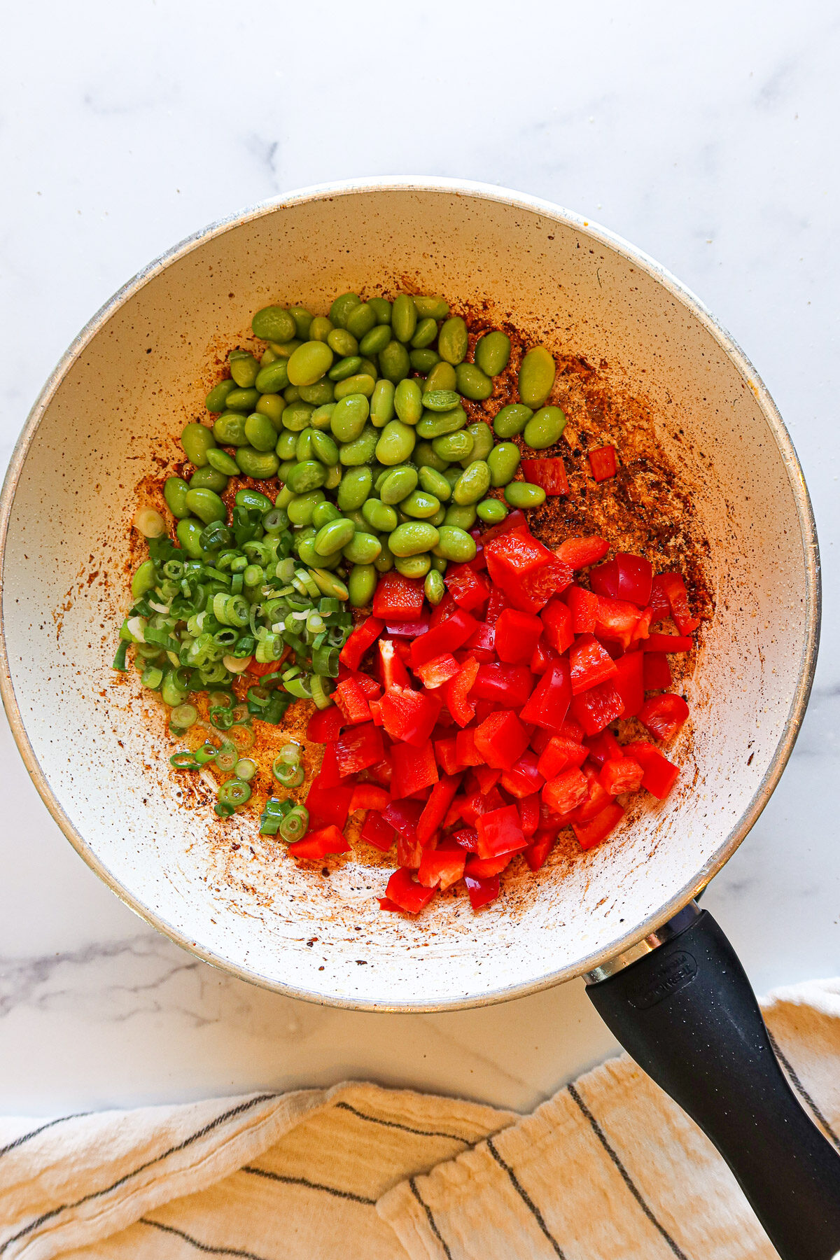Sautéing green onion, edamame and red bell pepper.