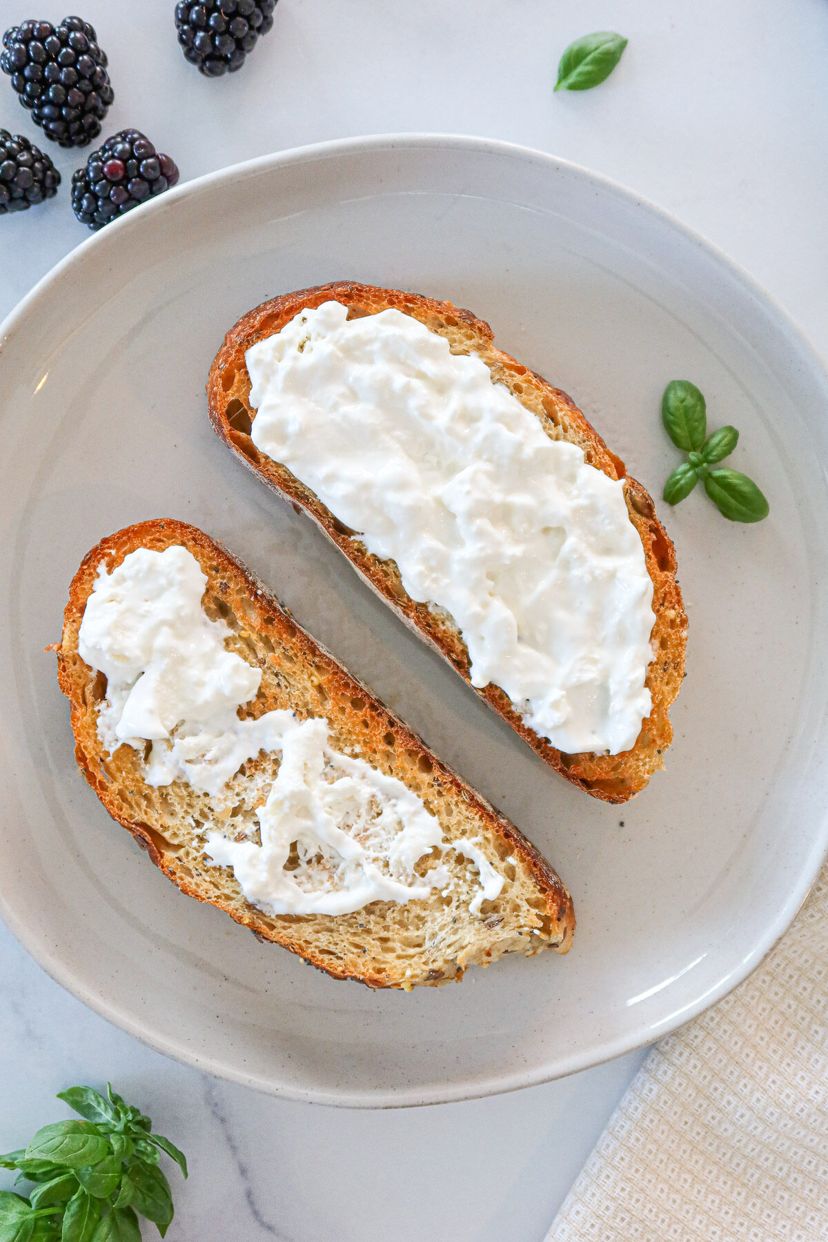 Spreading burrata cheese on top of the toast.