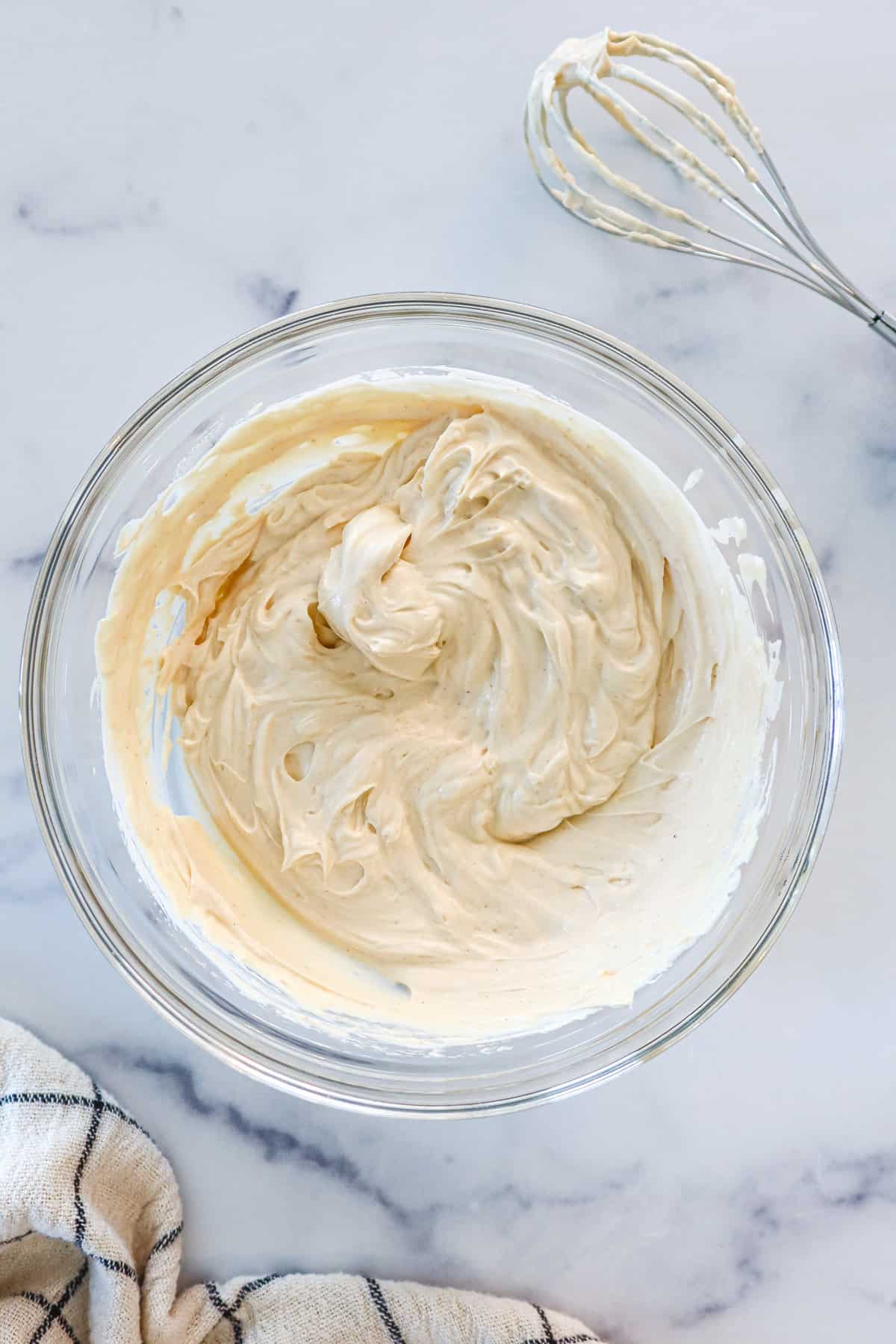 Yogurt peanut butter dip whisked up in a glass mixing bowl.