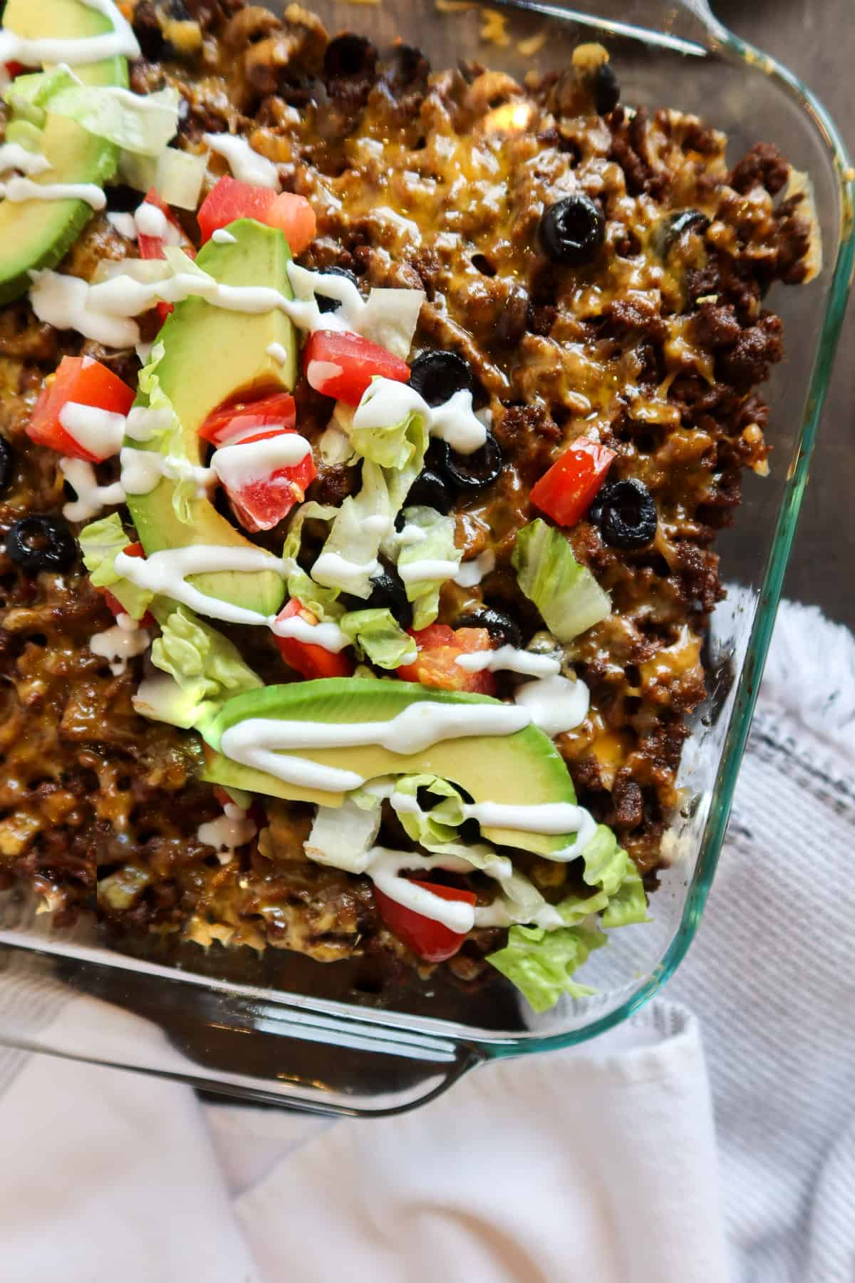 Keto taco casserole with toppings in a glass baking dish.