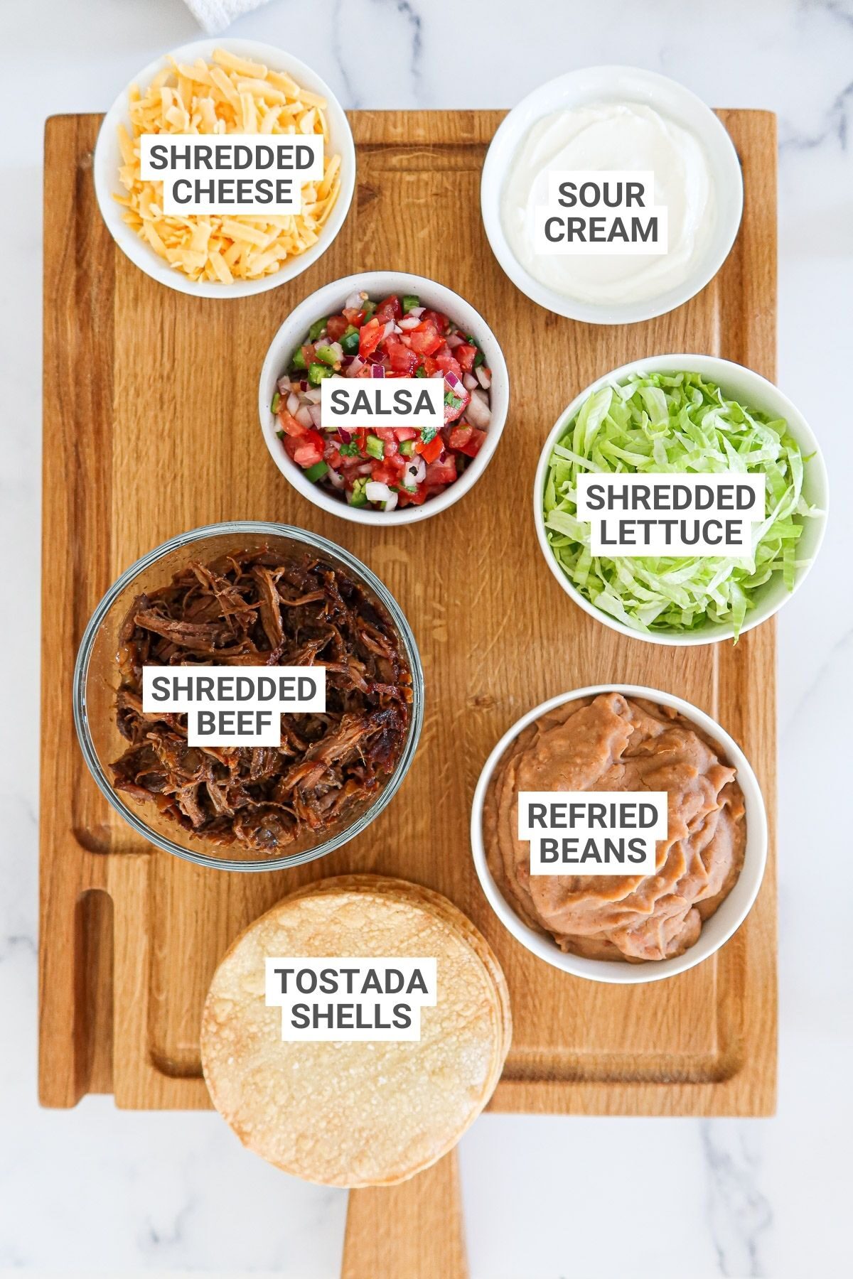 Ingredients for shredded beef tostadas with text overlay labels.