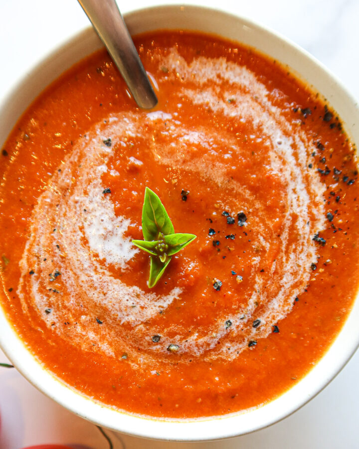 Creamy tomato basil soup in a white bowl.