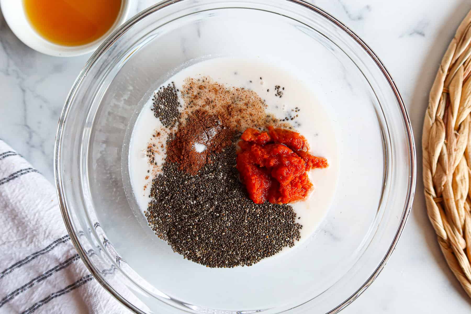 Ingredients for pumpkin chia pudding measured into a large, glass bowl.