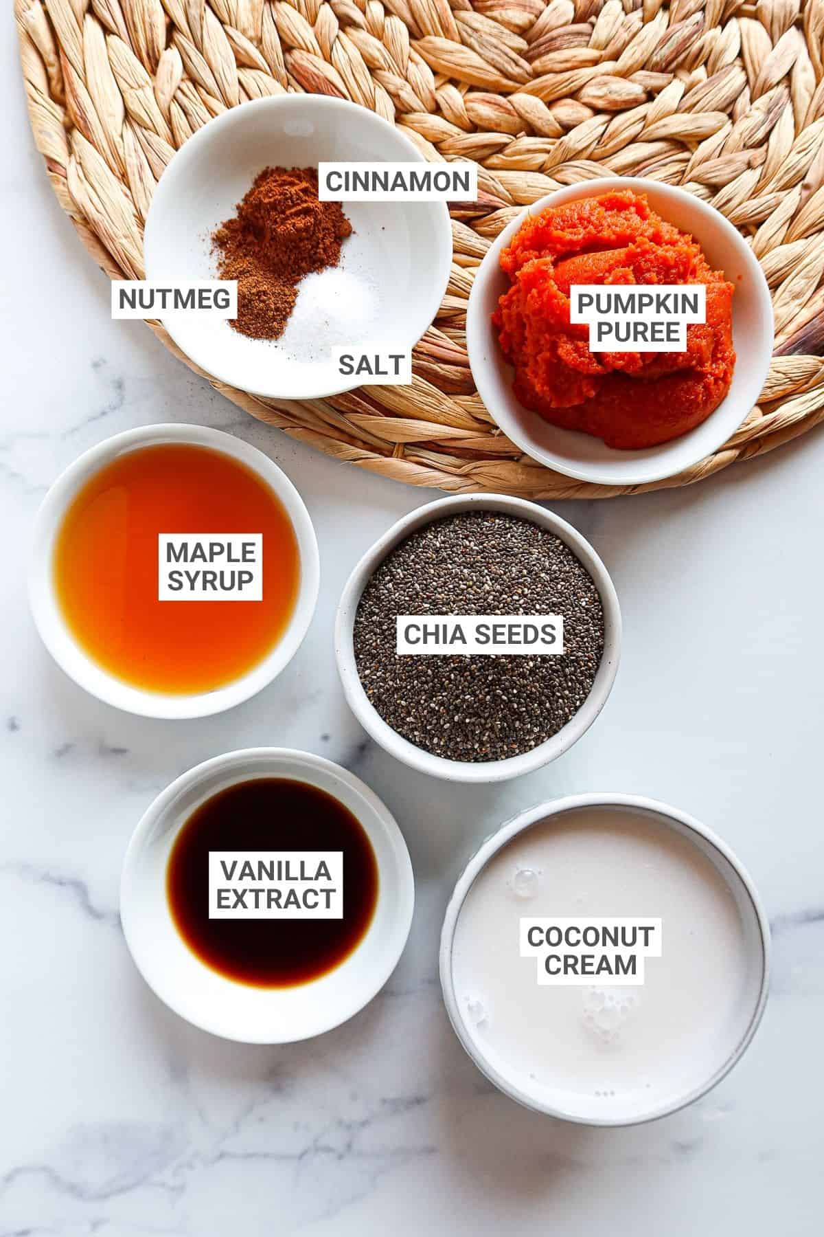 Ingredients for pumpkin chia pudding arranged on a white countertop with text overlay labels.