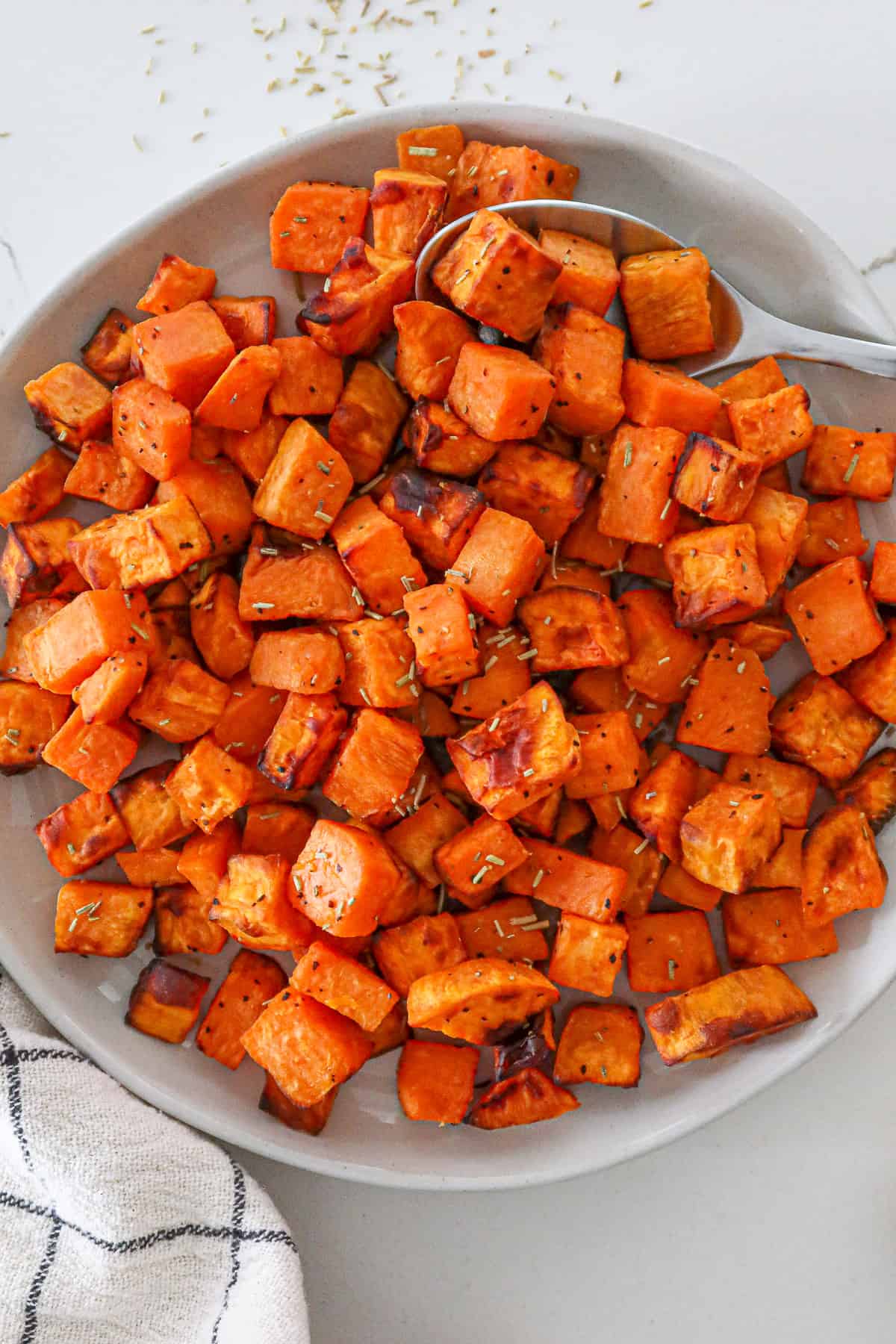 Close up of air fried sweet potato cubes in a white serving bowl.