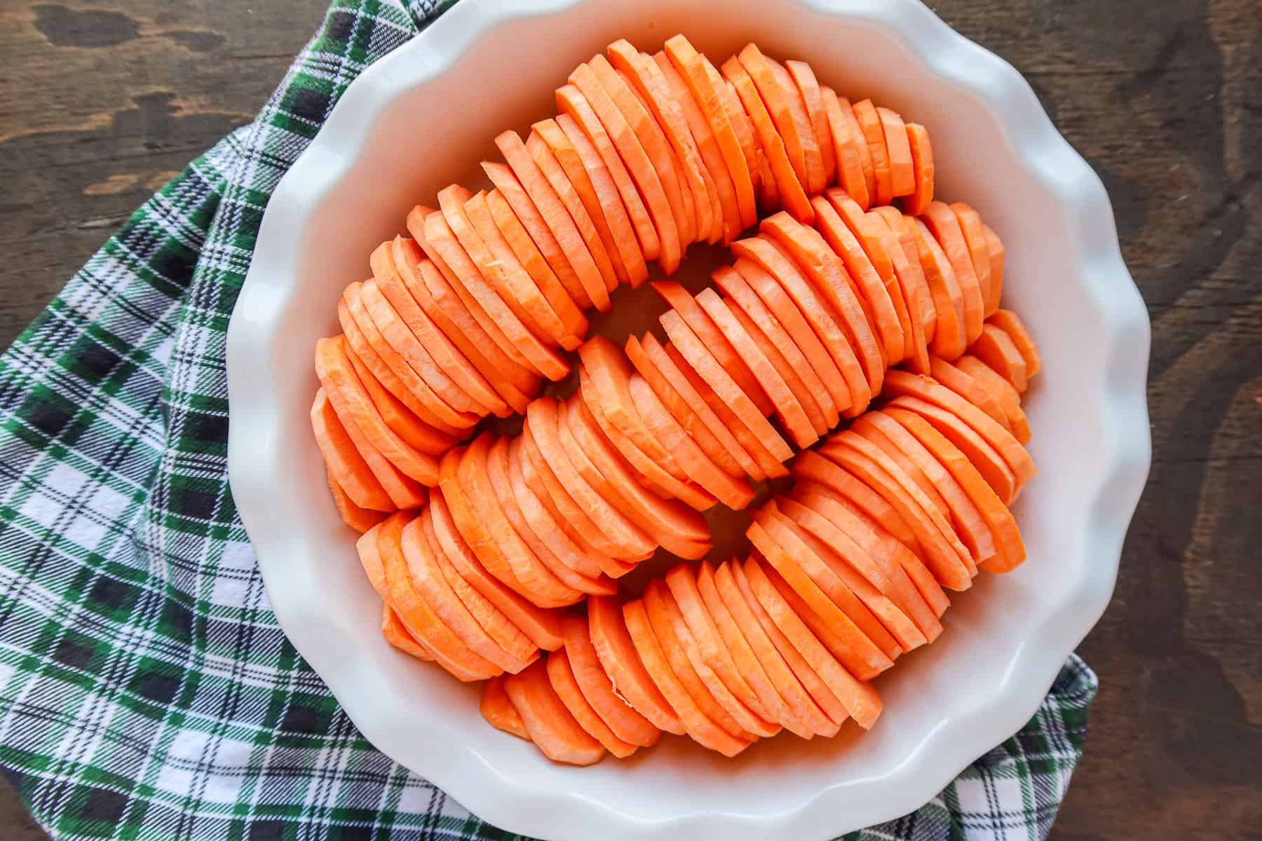 Sweet potato slices lined in a shallow pie baking dish.