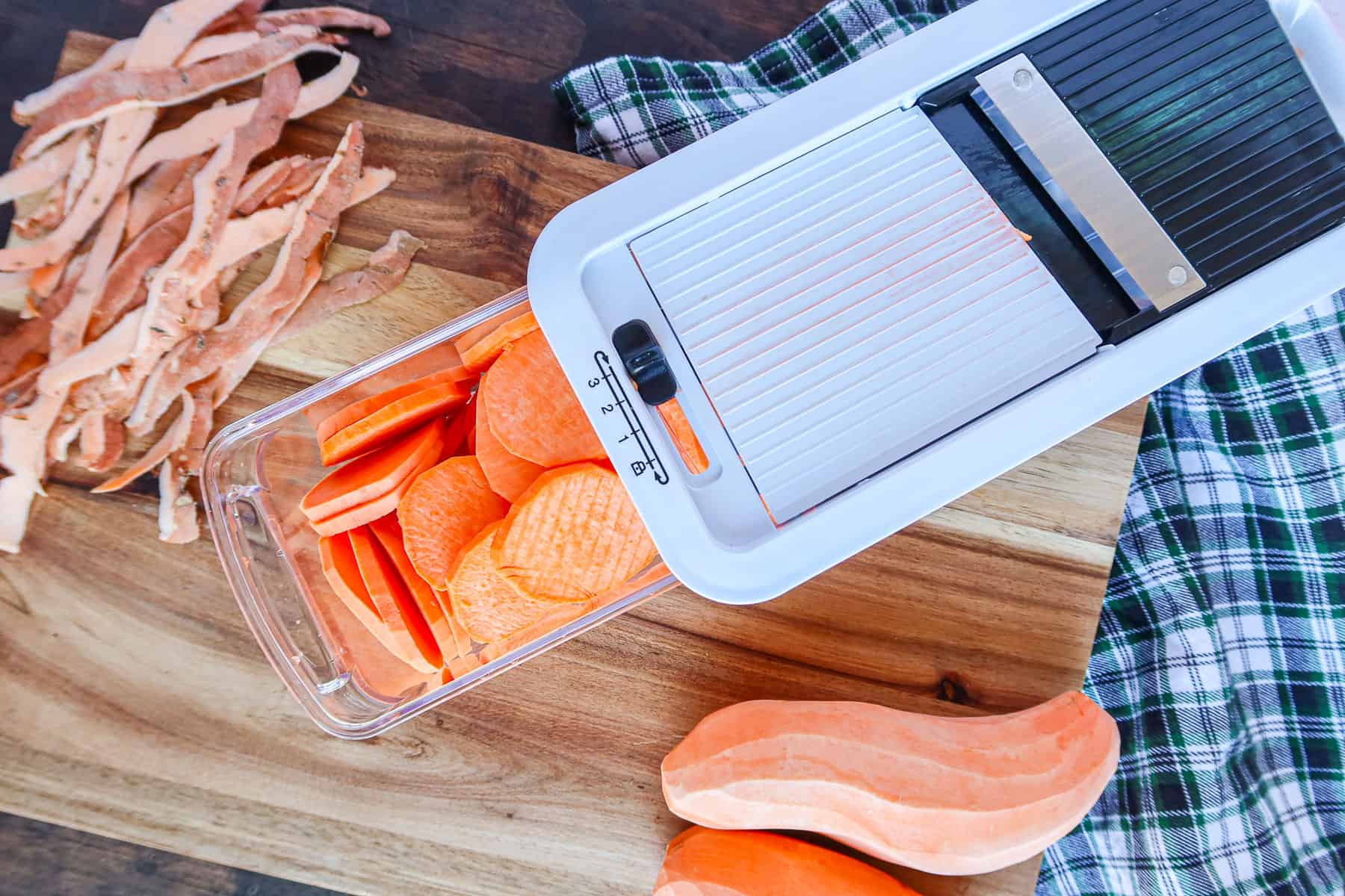 Cutting sweet potatoes into medallions with mandolin slicer.