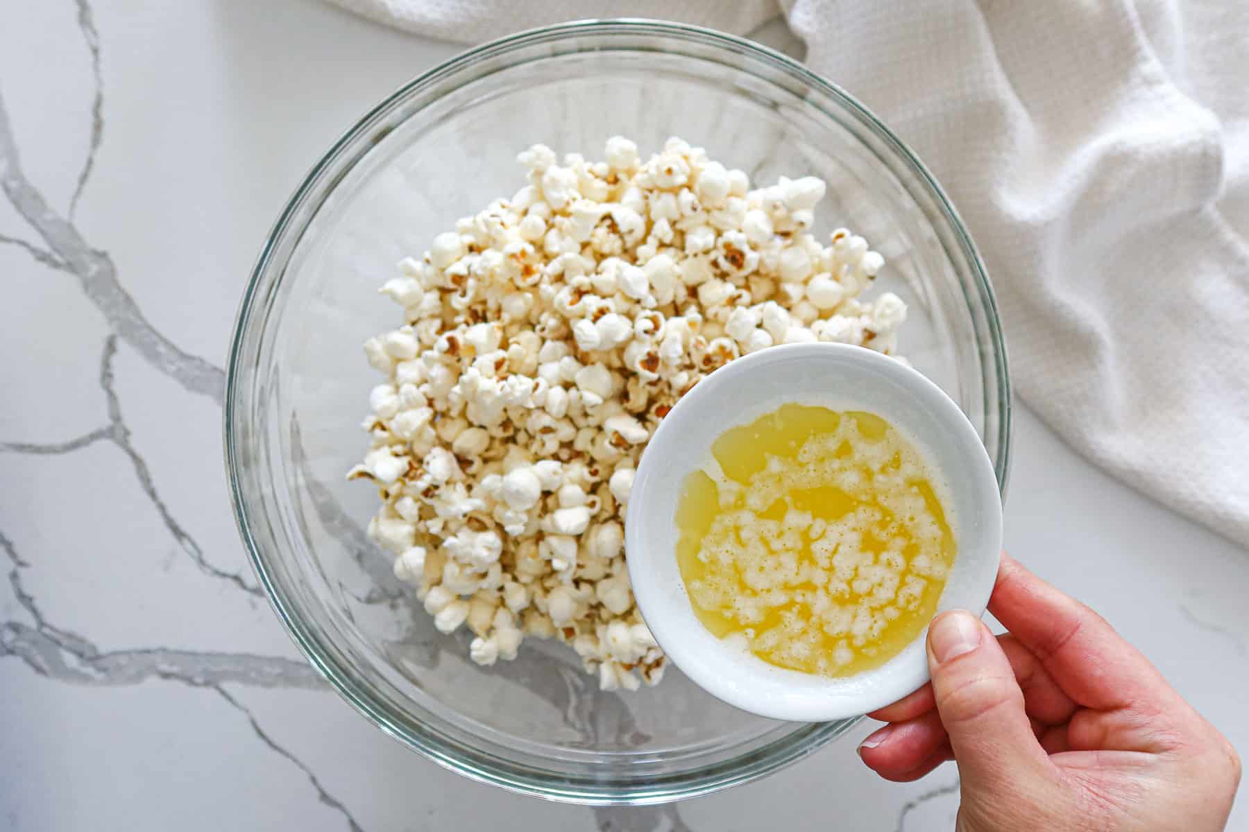 Pouring melted butter over popcorn.