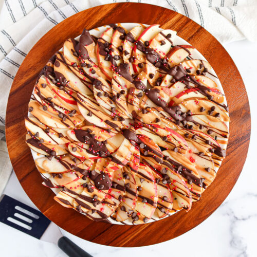 A platter of apple and pear slices drizzled in chocolate and peanut butter.