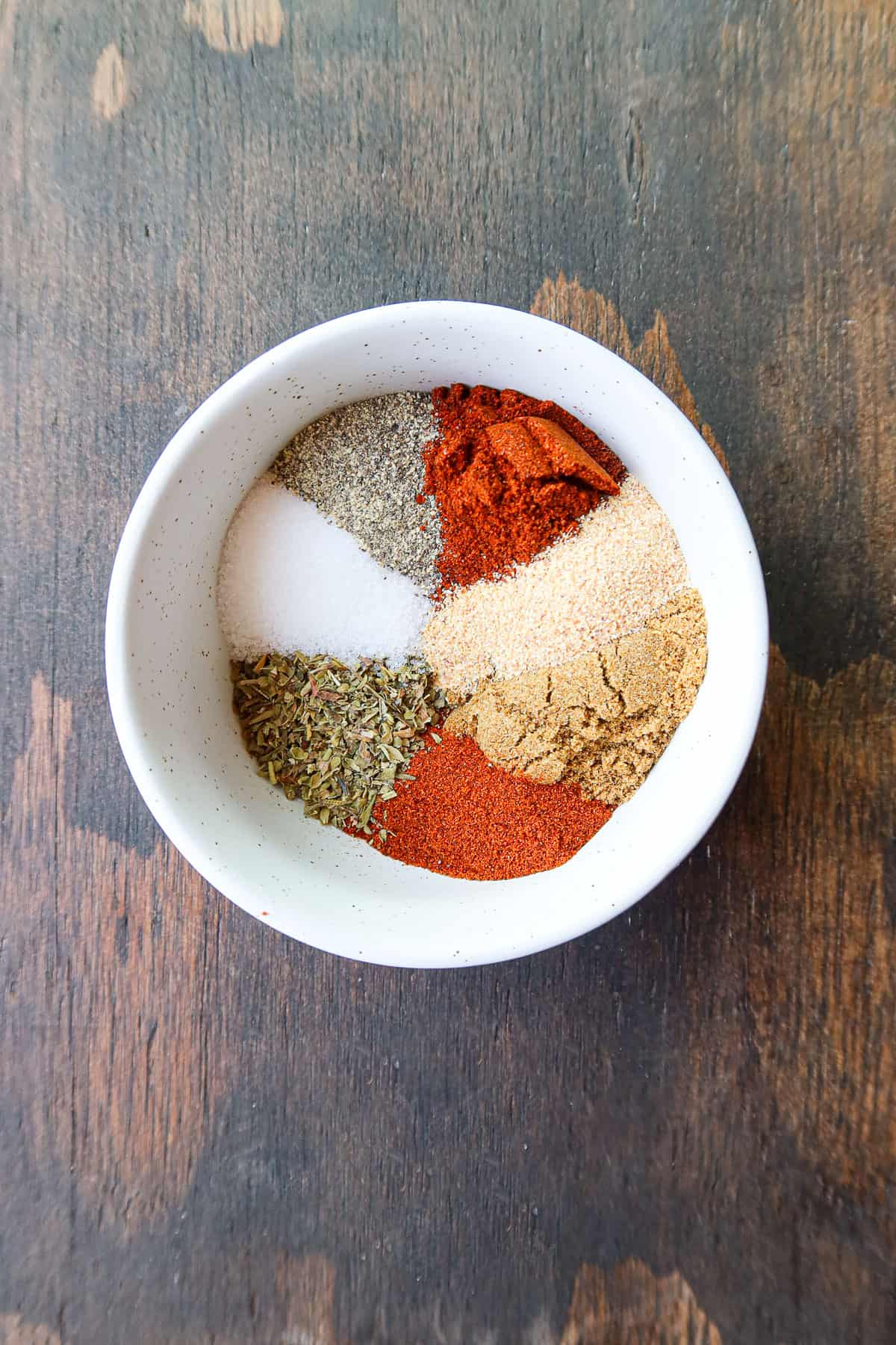 Spices for chili measured into a small, white bowl.