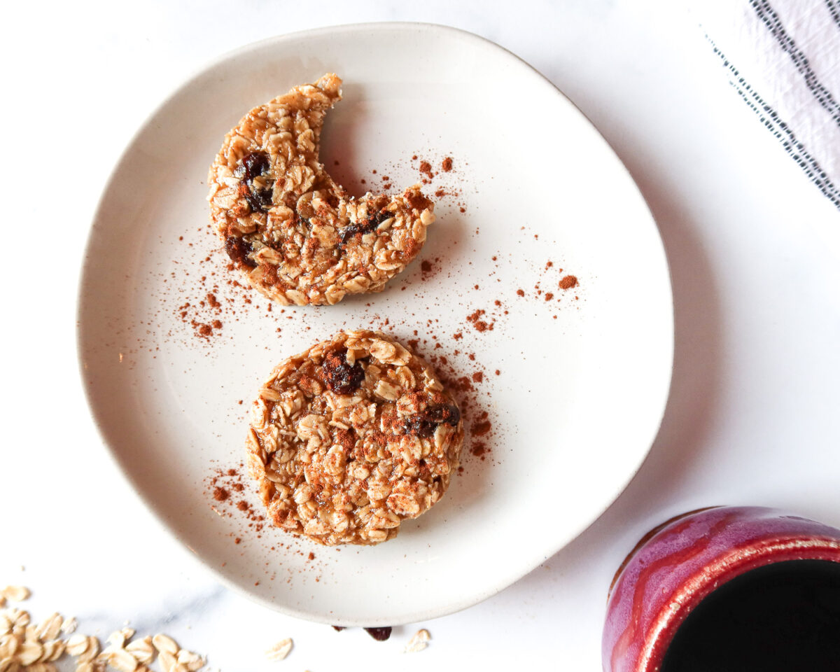 Two cookies on a plate with cinnamon, one is missing a bite.