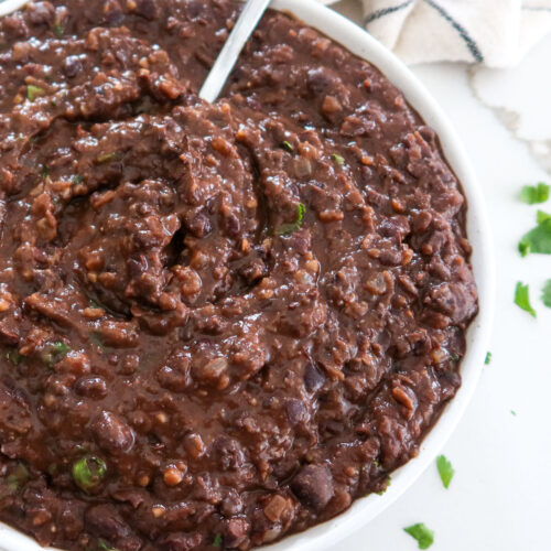 Refried black beans in a white serving bowl.