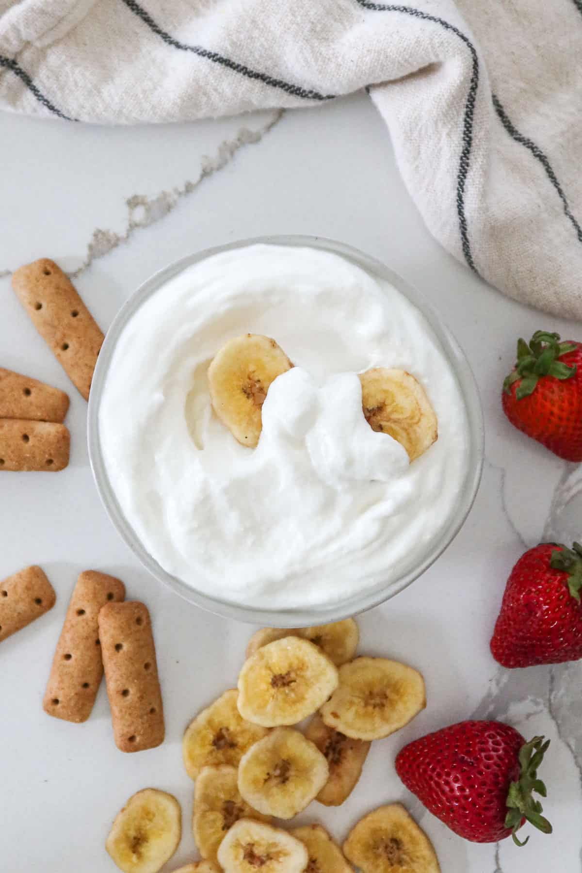 Whipped cottage cheese in a bowl with fruit and crackers to the side.