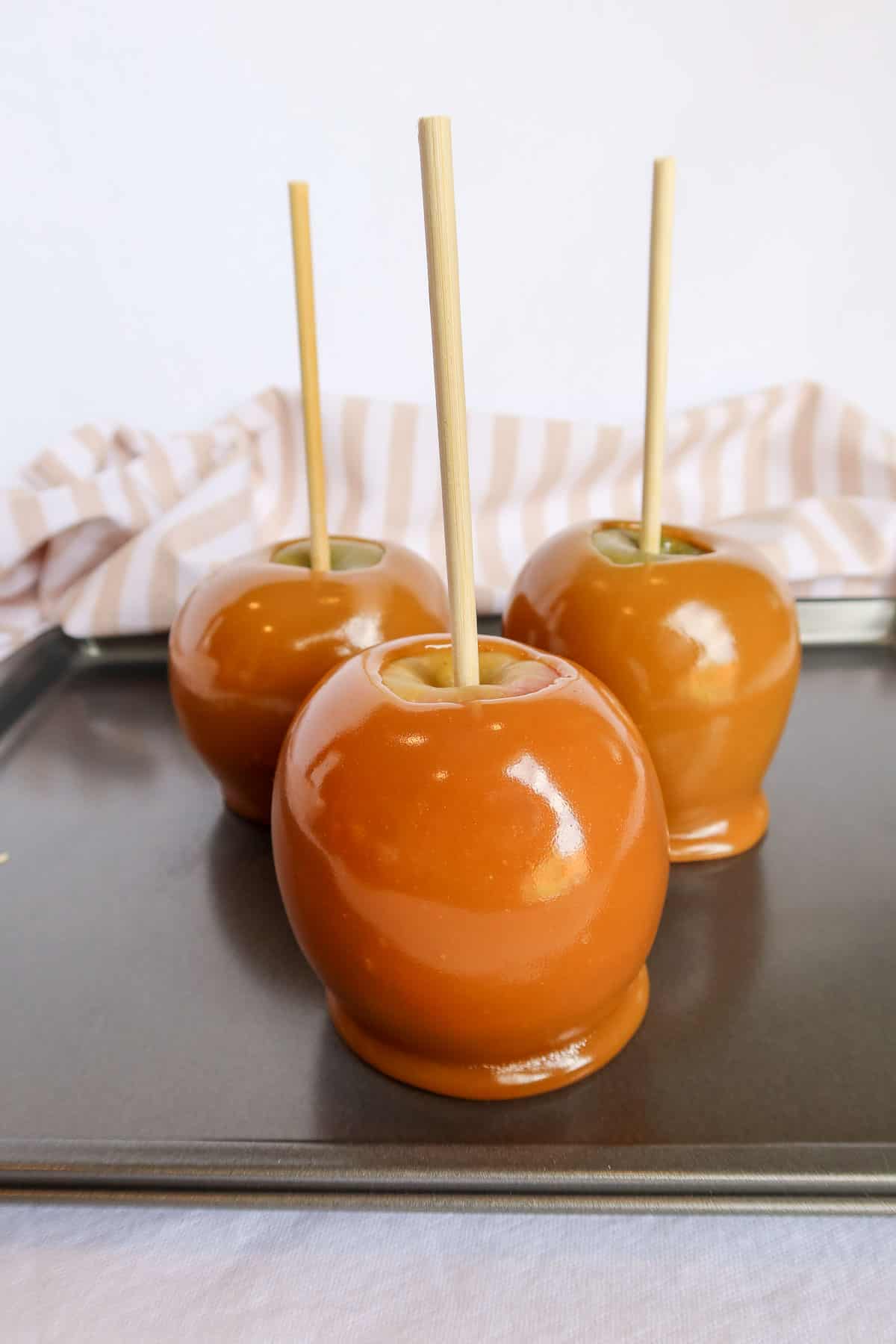 Caramel dipped apples on a baking sheet.