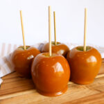 Caramel dipped apples on a cutting board.