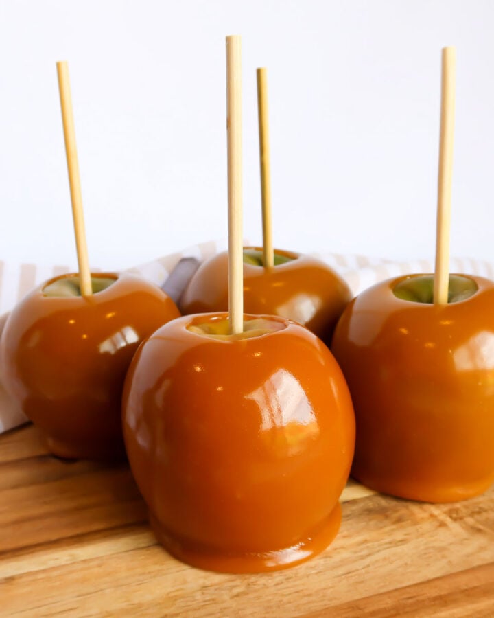 Caramel dipped apples on a cutting board.
