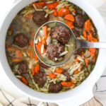 A ladle full of meatball orzo soup.