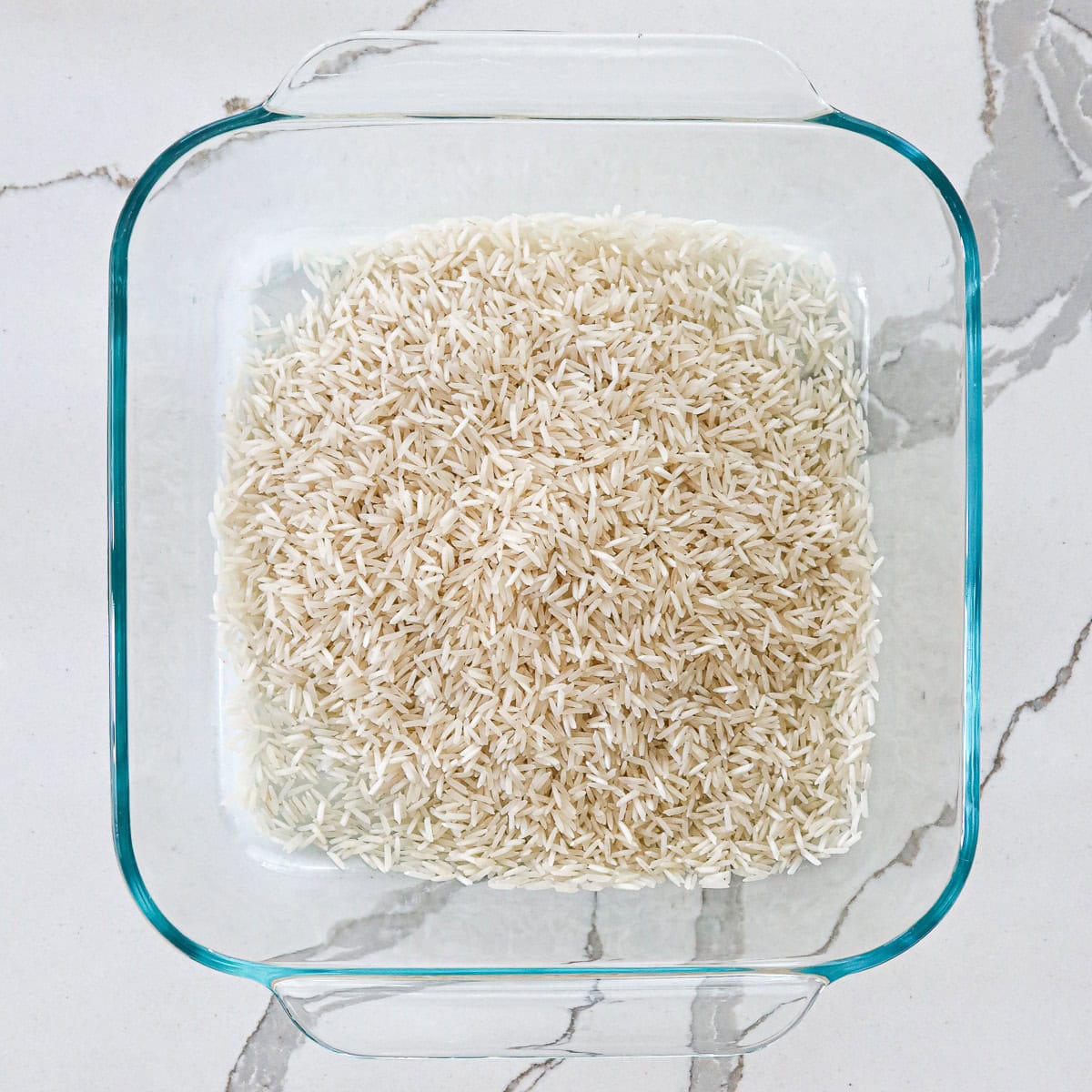 Uncooked white rice in a 9 by 9 inch baking dish.