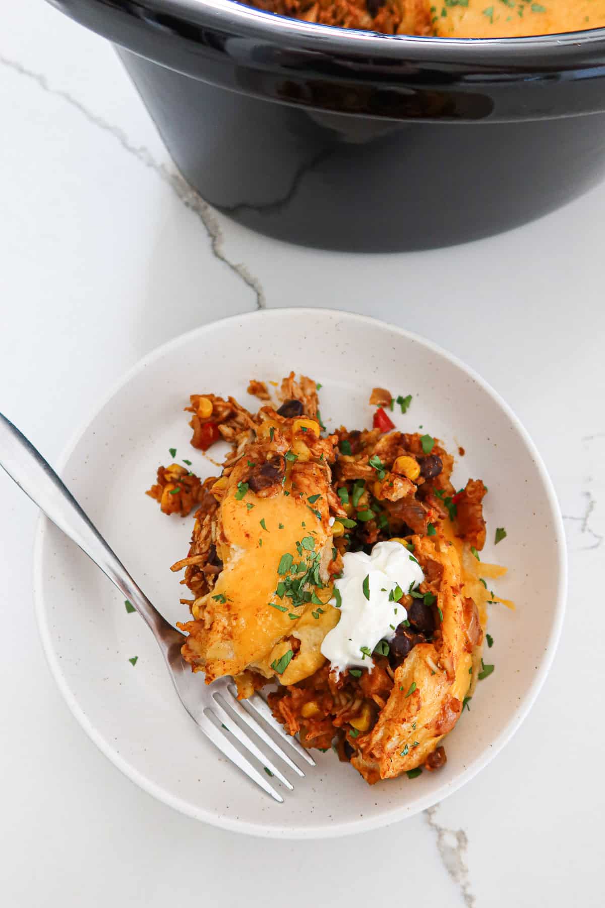 Piece of crockpot chicken enchilada casserole on a plate.