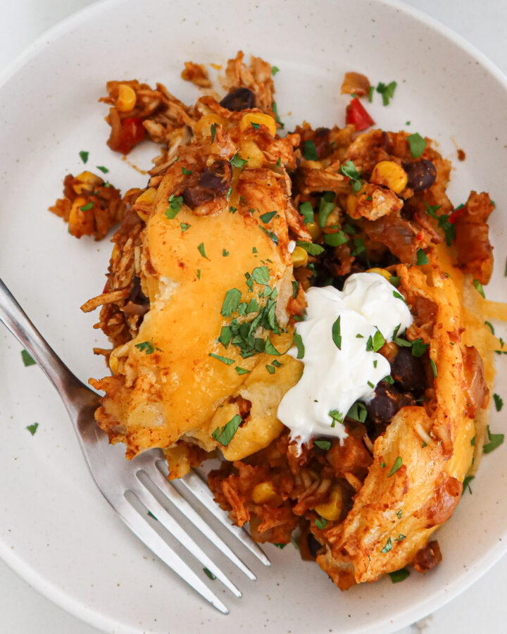 Piece of crockpot chicken enchilada casserole on a plate.