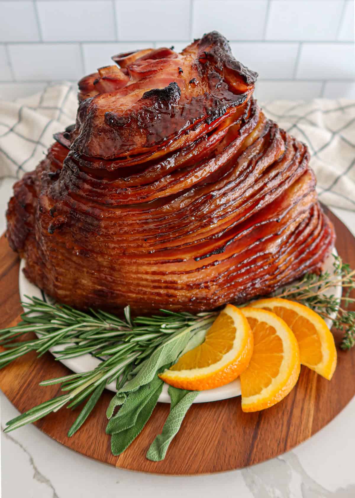 Baked spiral ham garnished with herbs and orange slices.