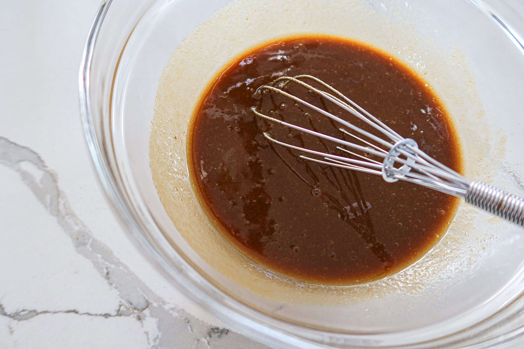 Brown sugar, honey dijon mustard and orange juice whisked together in a glass mixing bowl.