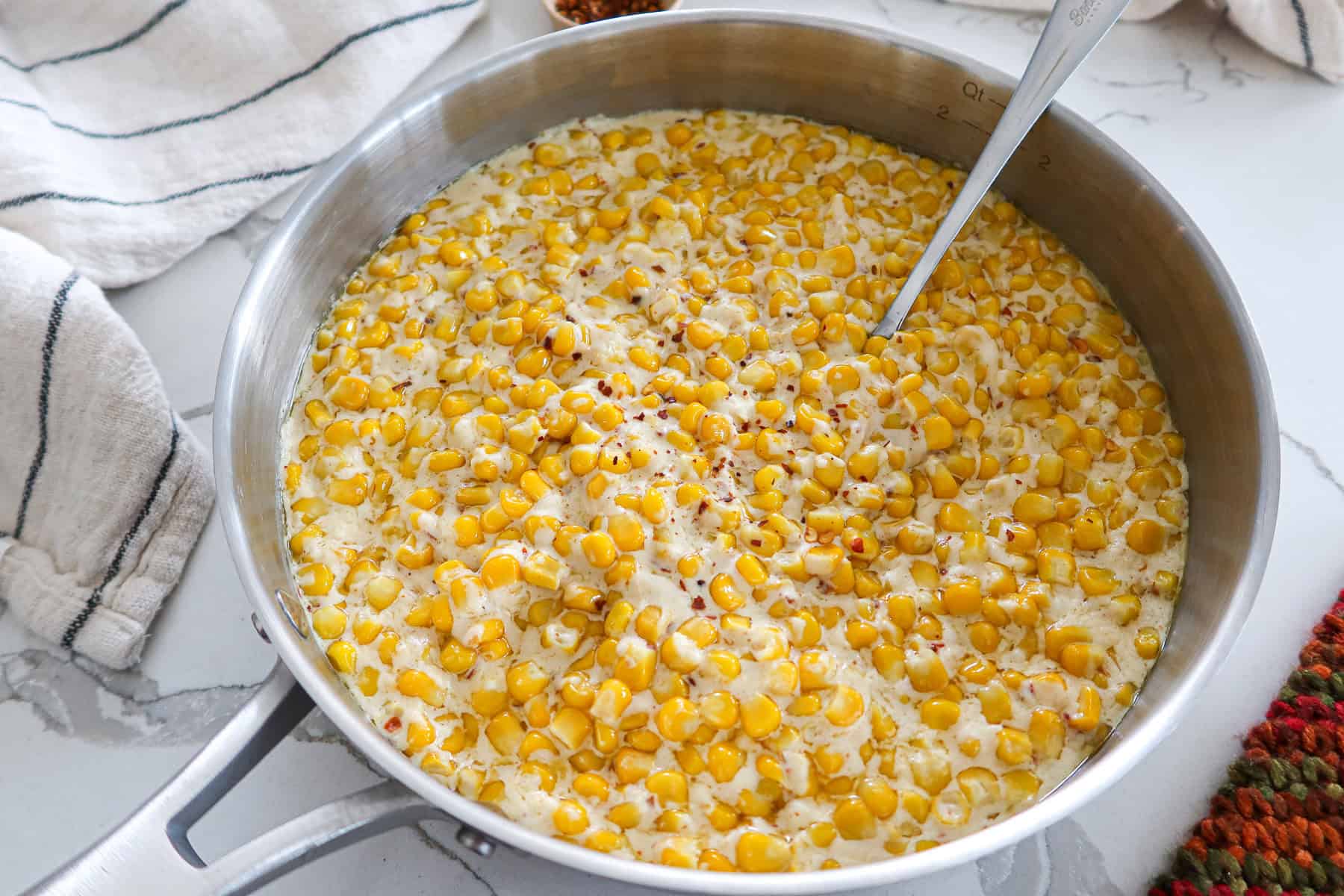Creamed corn in a large, stainless steel skillet.